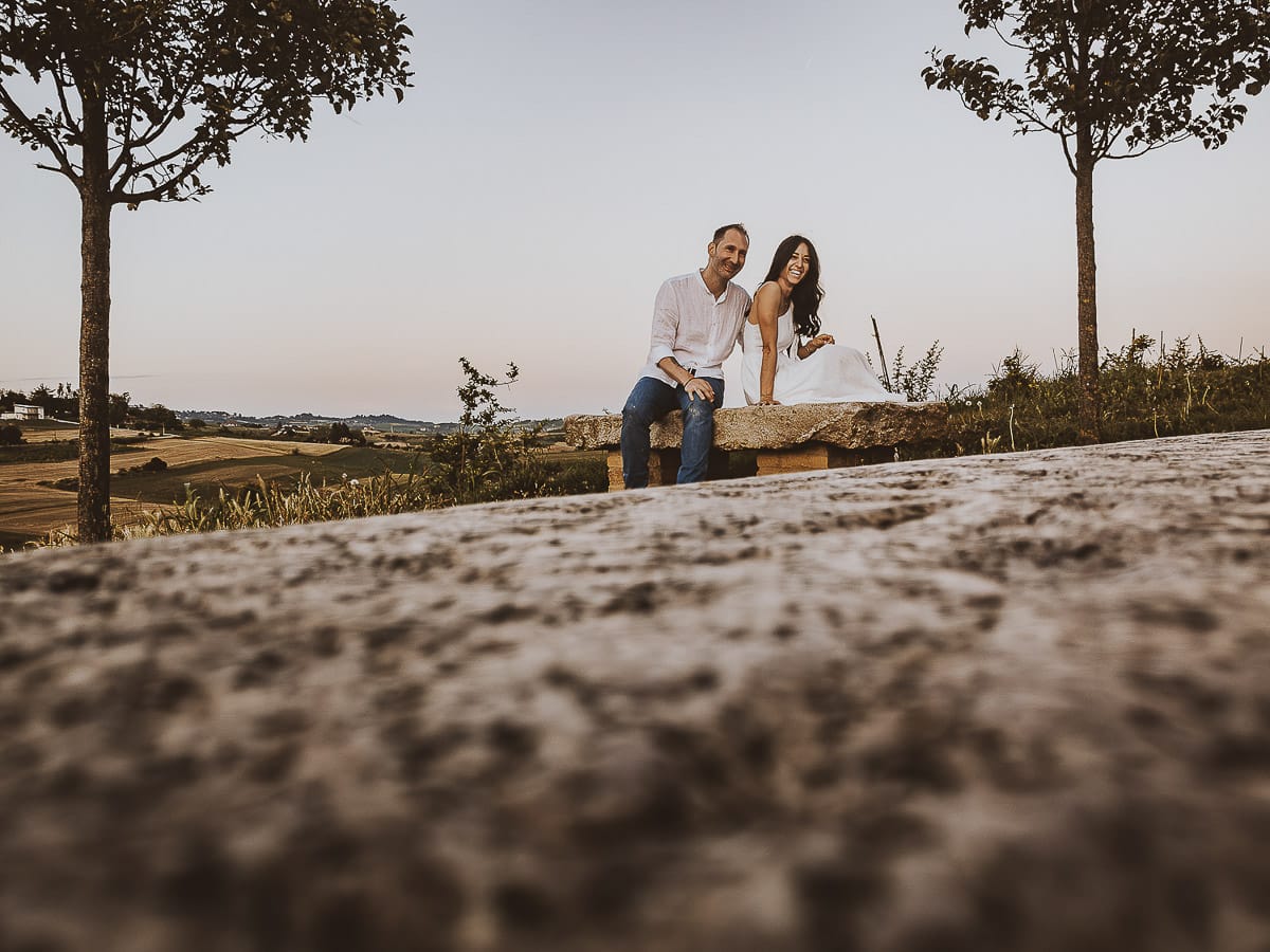 Prewedding romantico e da sogno al tramonto in Monferrato. Valeria e Omar seduti su di una panchina di pietra. Foto ripresa dal drone posto sul terreno.