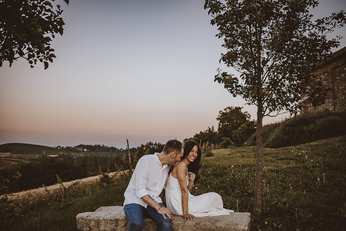 Prewedding romantico e da sogno al tramonto in Monferrato. Valeria e Omar seduti su di una panchina di pietra. Omar bacia la spalla di Valeria