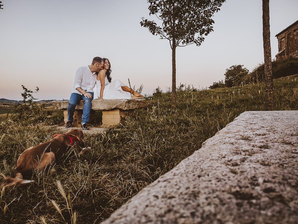 Prewedding romantico e da sogno al tramonto in Monferrato. Valeria e Omar seduti su di una panchina di pietra. Foto ripresa dal drone posto sul terreno.