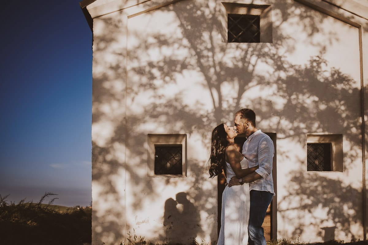Prewedding romantico e da sogno al tramonto in Monferrato. Valeria e Omar davanti alla chiesetta di san Lorenzo. L'ombra degli alberi crea una trama d'ombra molto interessante.