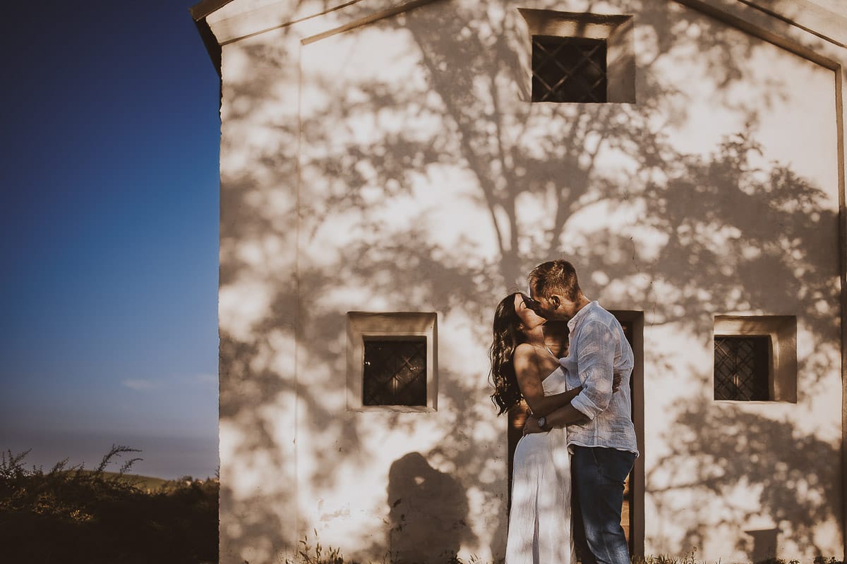 Prewedding romantico e da sogno al tramonto in Monferrato. Valeria e Omar davanti alla chiesetta di san Lorenzo. L'ombra degli alberi crea una trama d'ombra molto interessante.