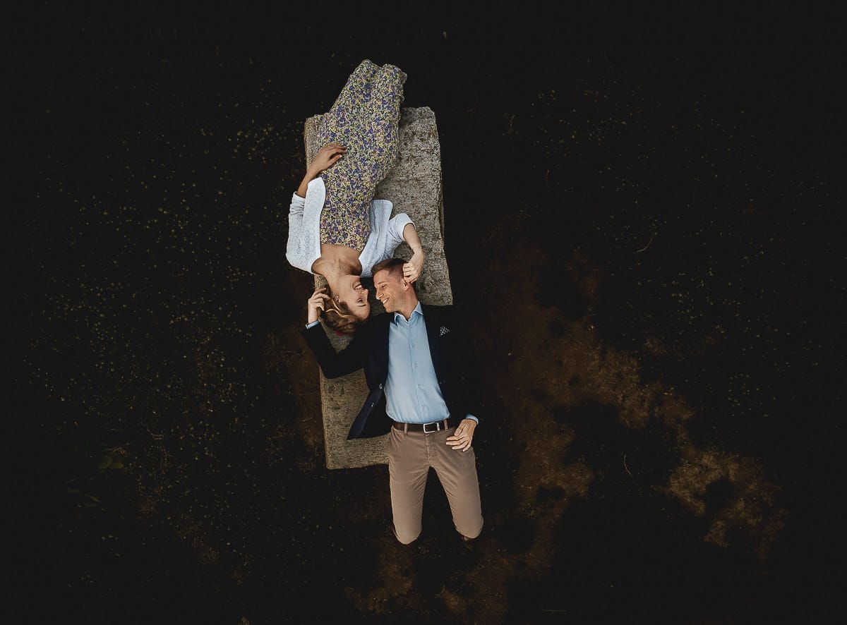 Prewedding primaverile in collina a Mombello di Torino di Federica e Mattia. La coppia è sdraiata su di una panchina di pietra. Foto aerea ripresa dal drone.