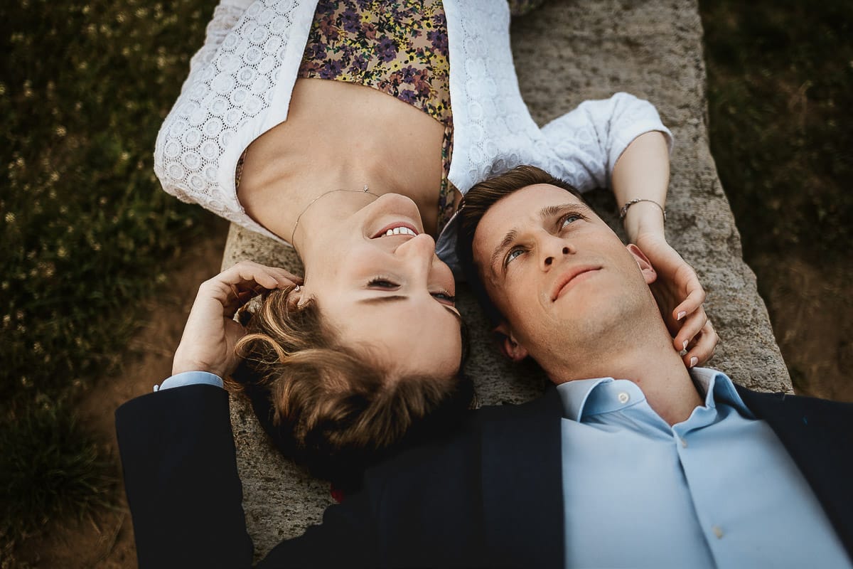 Prewedding primaverile in collina a Mombello di Torino di Federica e Mattia. La coppia è sdraiata su di una panchina di pietra.