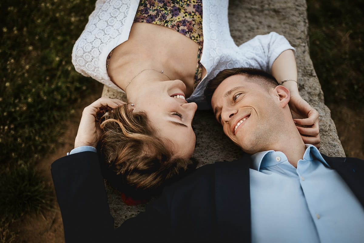 Prewedding primaverile in collina a Mombello di Torino di Federica e Mattia. La coppia è sdraiata su di una panchina di pietra.