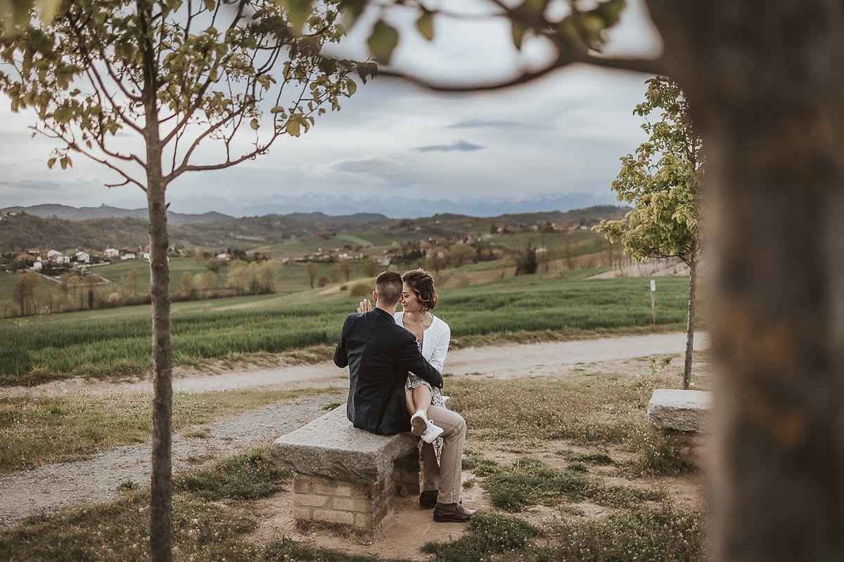 Prewedding primaverile in collina a Mombello di Torino di Federica e Mattia. La coppia è seduta sulla panchina di pietra e si guarda.