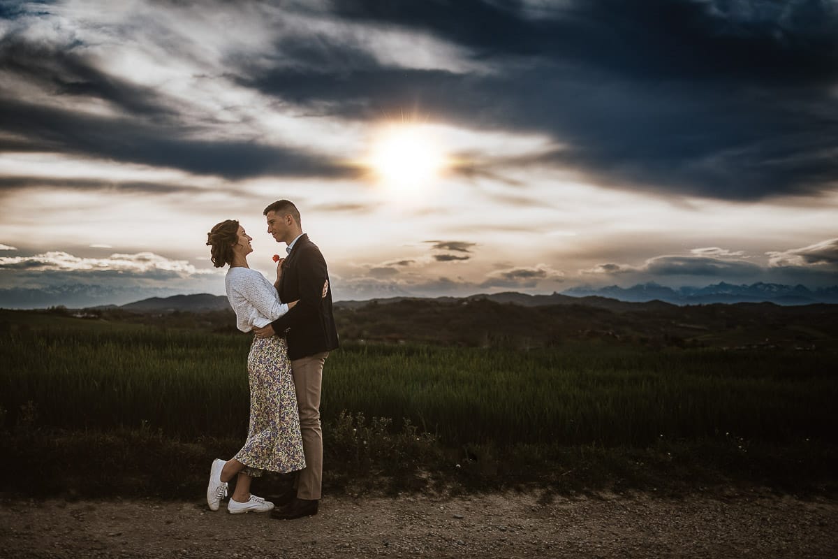 Prewedding primaverile in collina a Mombello di Torino di Federica e Mattia. Ritratto in controluce con il sole che sta tramontando fra le nuvole.