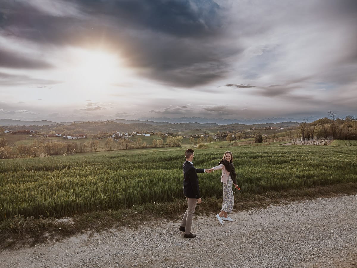 Prewedding primaverile in collina a Mombello di Torino di Federica e Mattia. Federica e Mattia camminano. Federica tira Mattia.