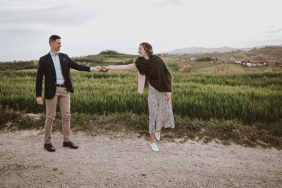 Prewedding primaverile in collina a Mombello di Torino di Federica e Mattia. Federica e Mattia camminano. Federica tira Mattia.