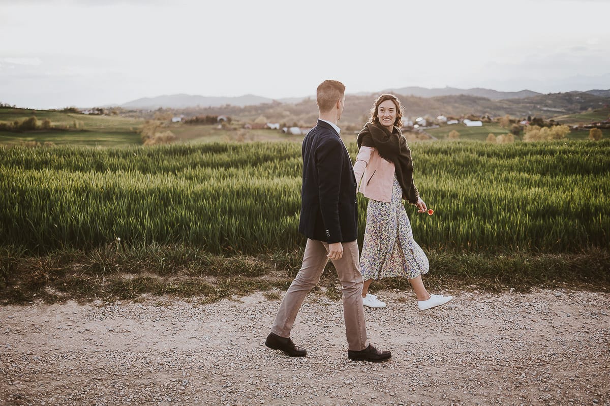 Prewedding primaverile in collina a Mombello di Torino di Federica e Mattia. Federica e Mattia camminano. Federica tira Mattia.