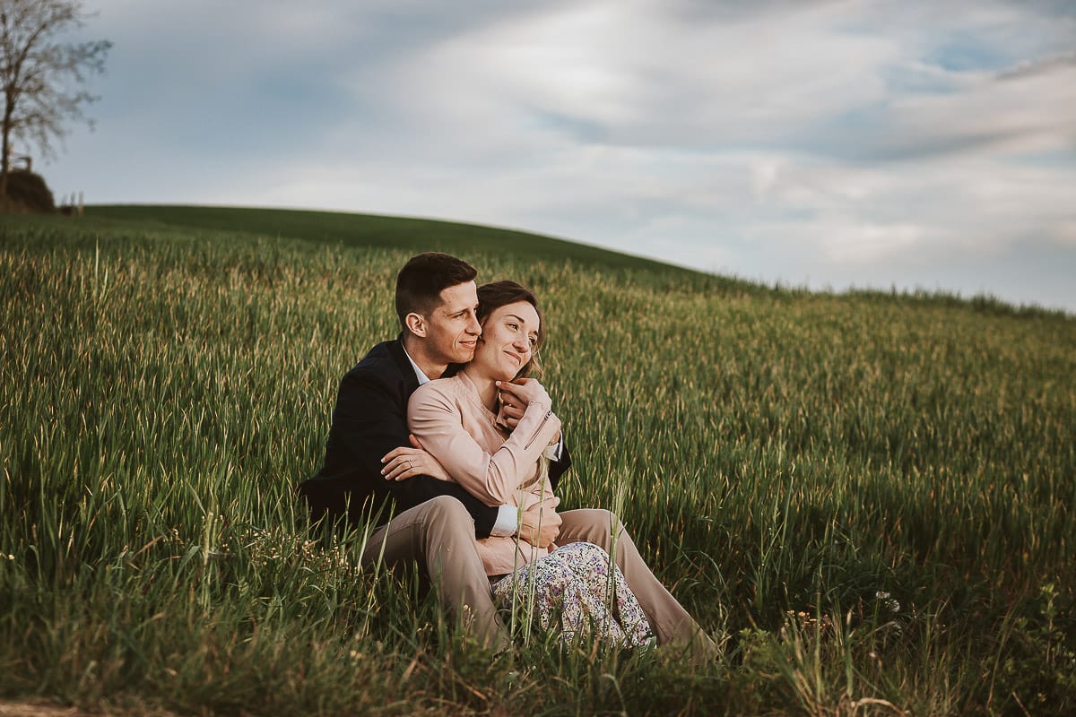 Prewedding primaverile in collina a Mombello di Torino di Federica e Mattia. Federica e Mattia sono seduti in un campo di grano ancora verde.