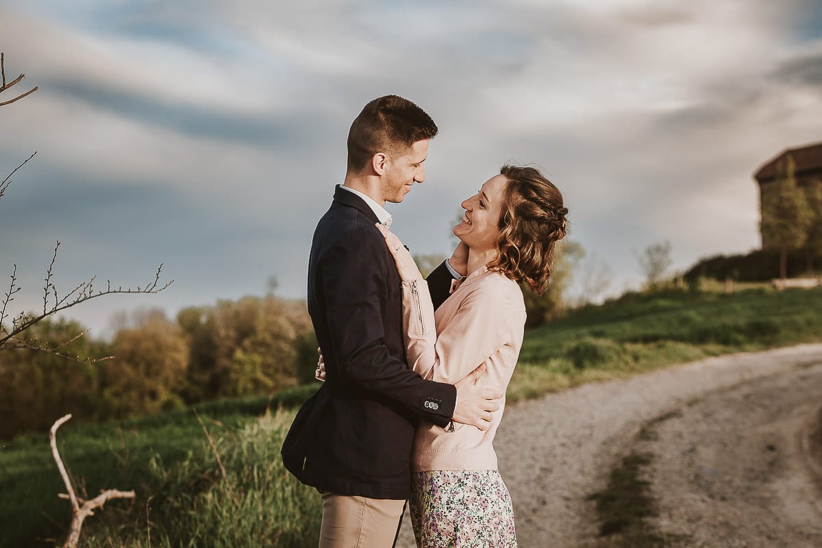 Prewedding primaverile in collina a Mombello di Torino di Federica e Mattia. Federica e Mattia si guardano. Dietro il cielo nuvoloso è bellissimo.