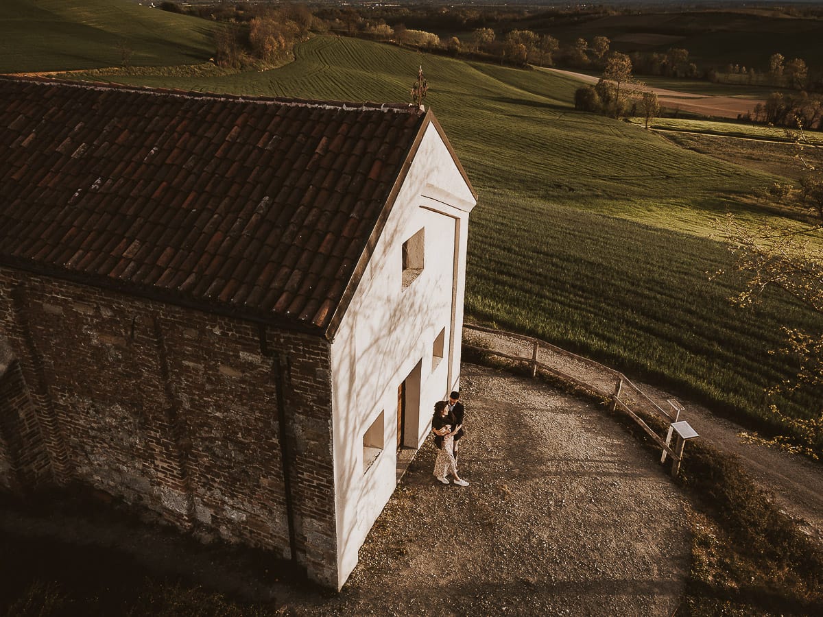 Prewedding primaverile in collina a Mombello di Torino di Federica e Mattia. Federica e Mattia di fronte alla chiesa di San Lorenzo. Foto ripresa dal drone.