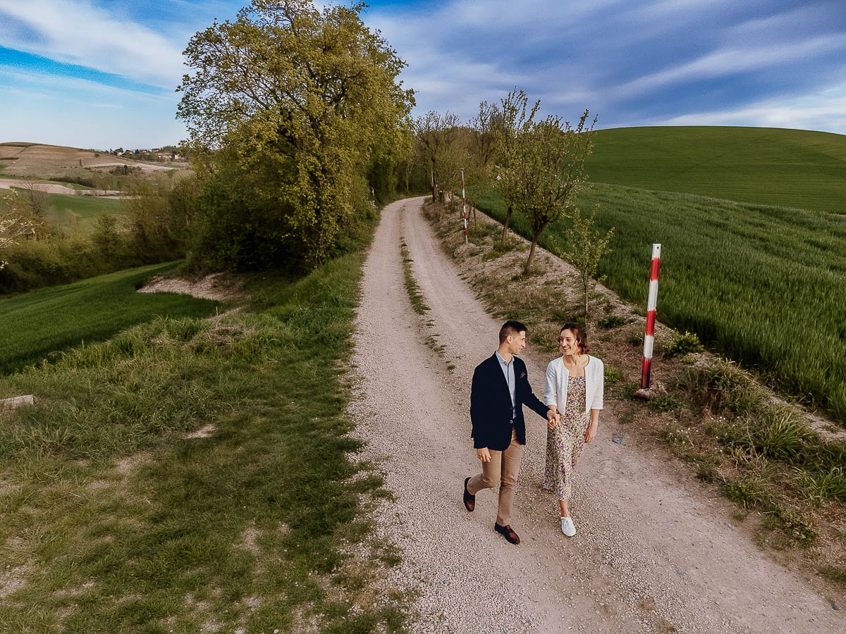 Prewedding primaverile in collina a Mombello di Torino di Federica e Mattia. La coppia cammina tenendosi per mano. Foto dal drone.