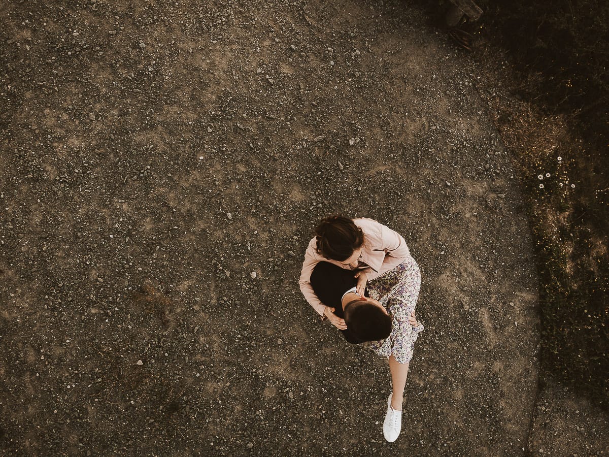 Prewedding primaverile in collina a Mombello di Torino di Federica e Mattia. Federica e Mattia di fronte alla chiesa di San Lorenzo. Mattia prende in braccio Federica. Foto dal drone.
