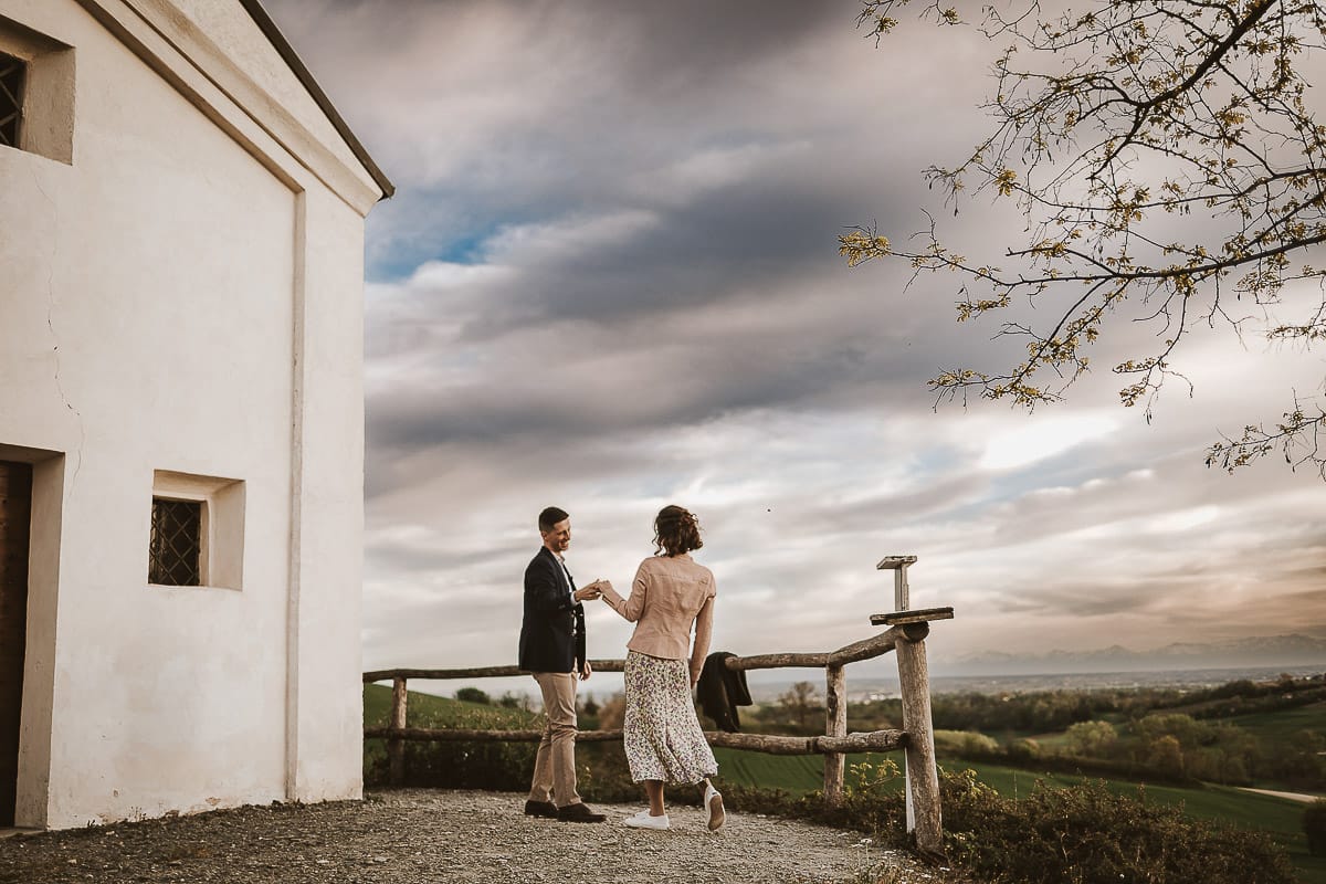 Prewedding primaverile in collina a Mombello di Torino di Federica e Mattia. Federica e Mattia di fronte alla chiesa di San Lorenzo. Mattia e Federica ballano