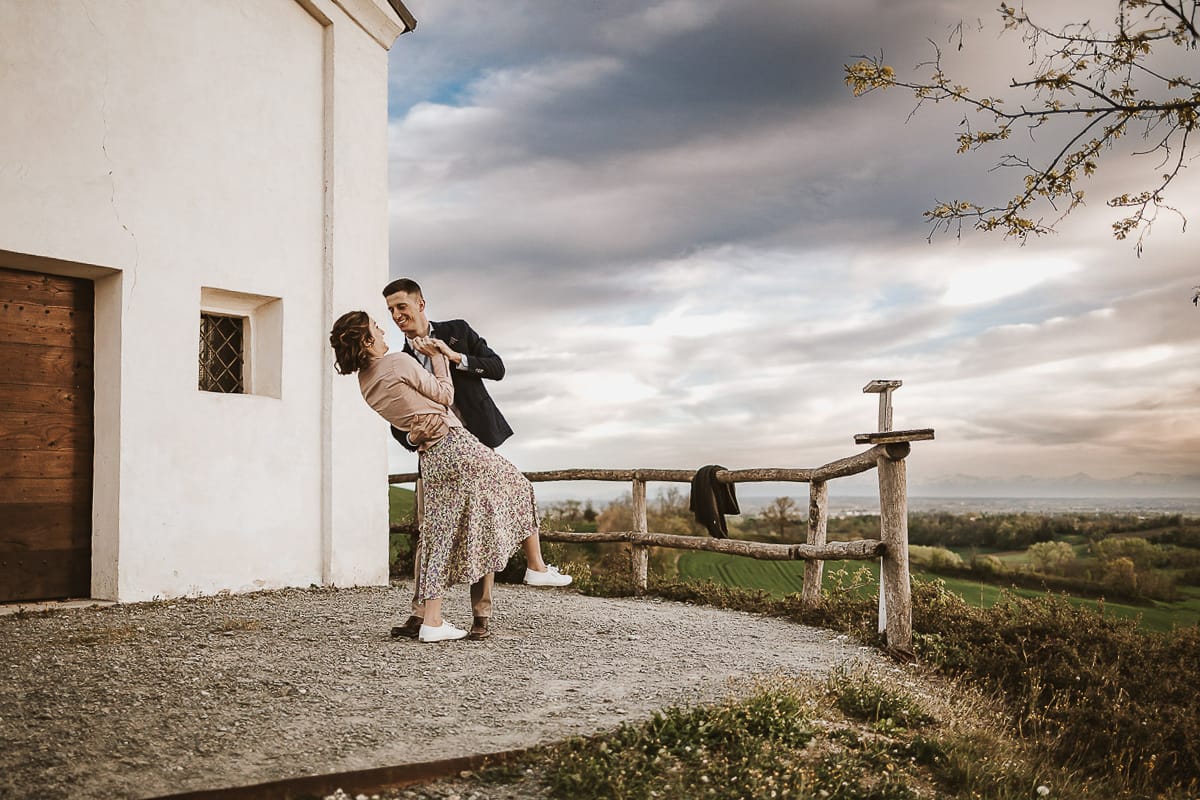 Prewedding primaverile in collina a Mombello di Torino di Federica e Mattia. Federica e Mattia di fronte alla chiesa di San Lorenzo. Mattia e Federica ballano con il casquet.