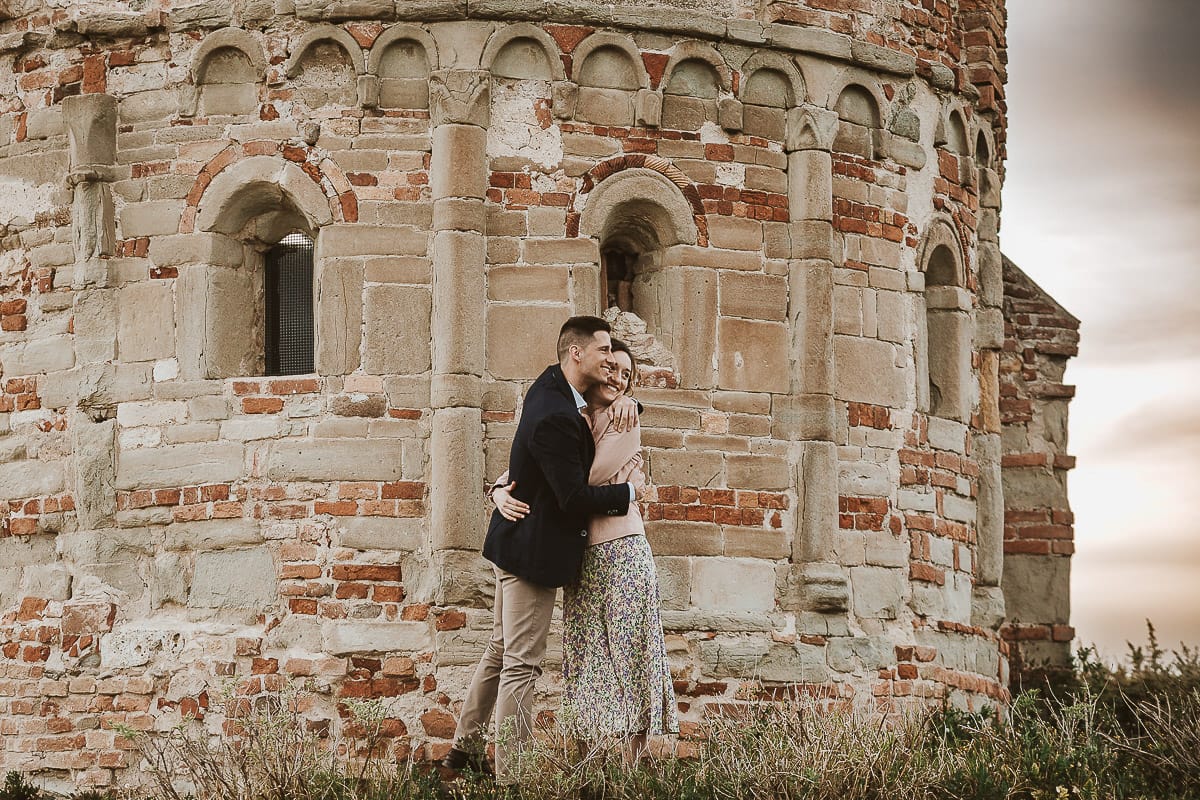 Prewedding primaverile in collina a Mombello di Torino di Federica e Mattia. Federica e Mattia di fronte alla chiesa di San Lorenzo. Mattia e Federica si abbracciano