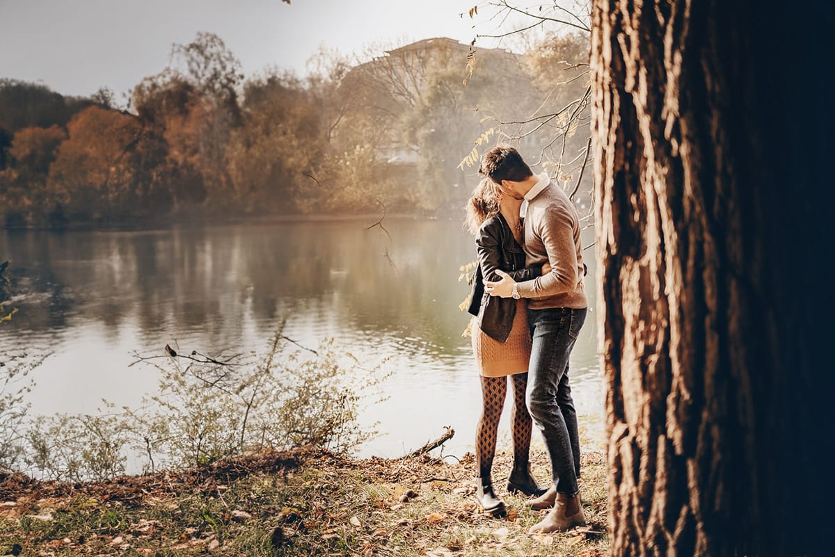 servizio fotografico prewedding da favola sul Lungo Po di Torino con il foliage autunnale. Cristina e Andrea si baciano davanti agli alberi sul Po che si riflettono nell'acqua