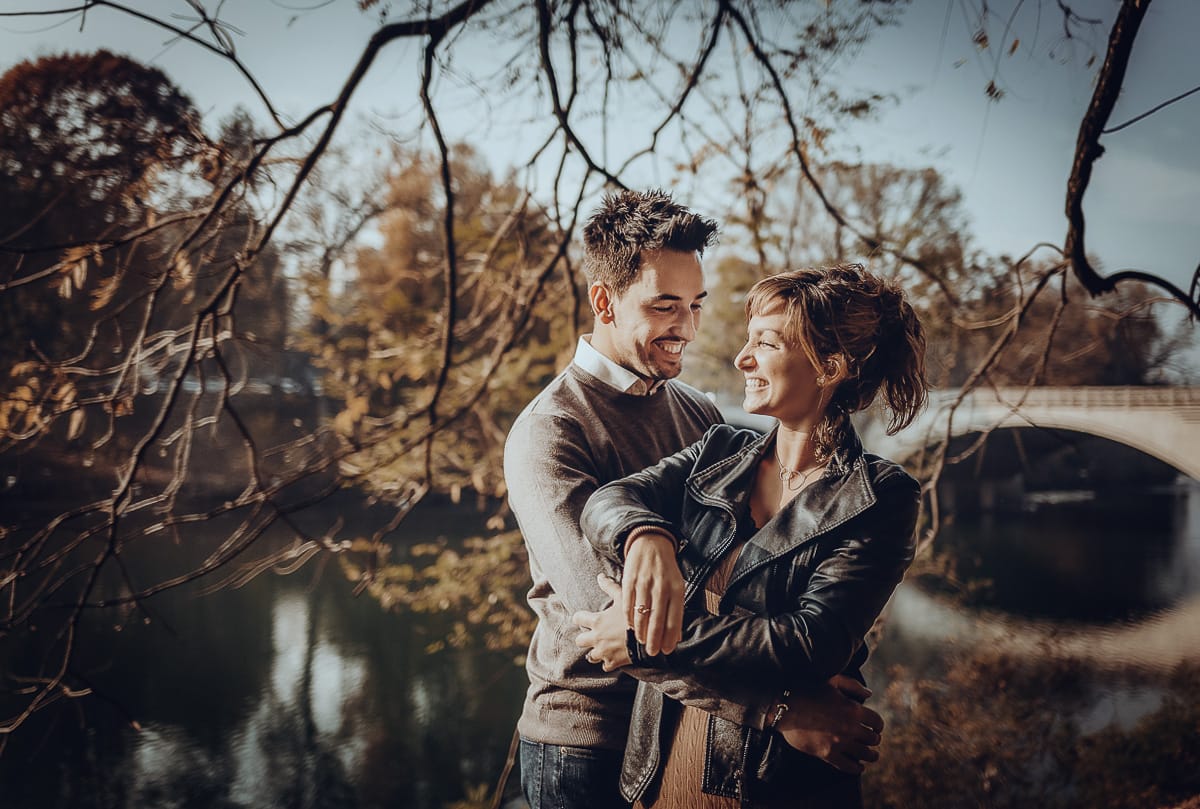 servizio fotografico prewedding da favola sul Lungo Po di Torino con il foliage autunnale. Cristina e Andrea si abbracciano davanti al ponte sul Po che si riflette nell'acqua