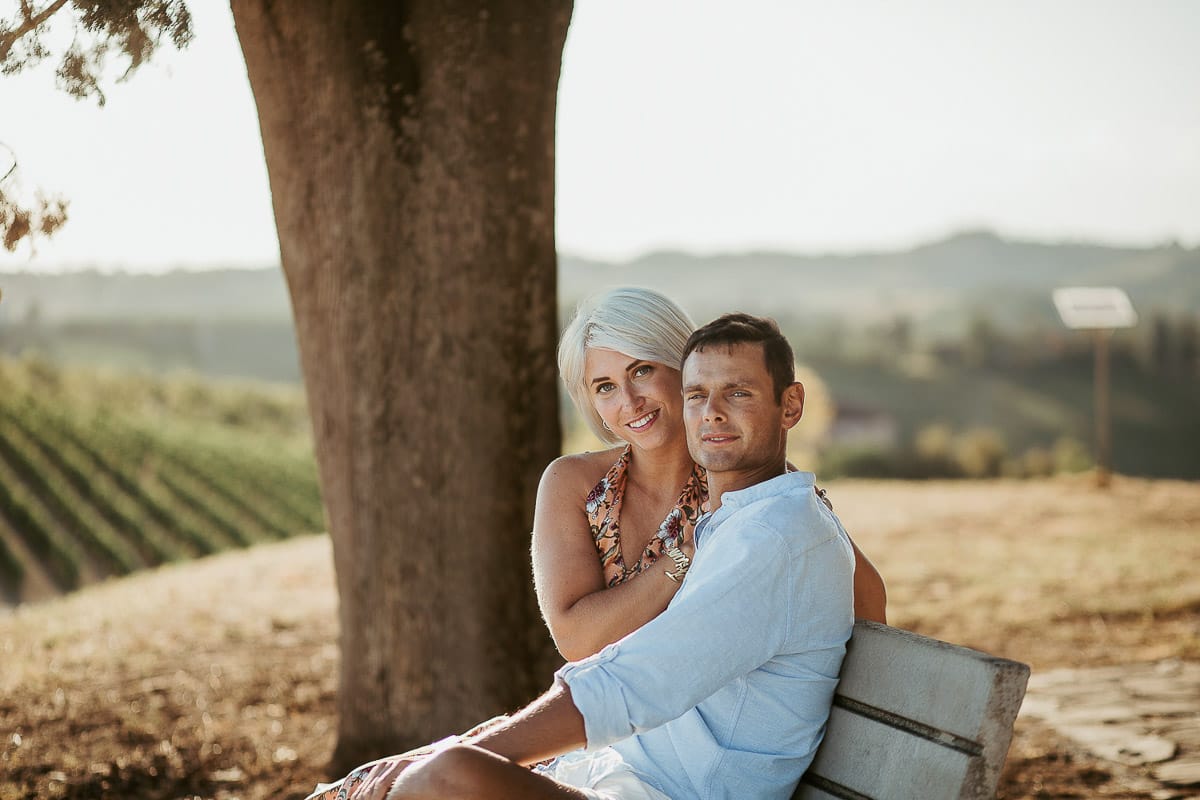 Prewedding da sogno a Nizza Monferrato intorno alla chiesa della Madonna della Neve. Matteo e Fiammetta seduti su di una panchina all'ombra di un grande albero.