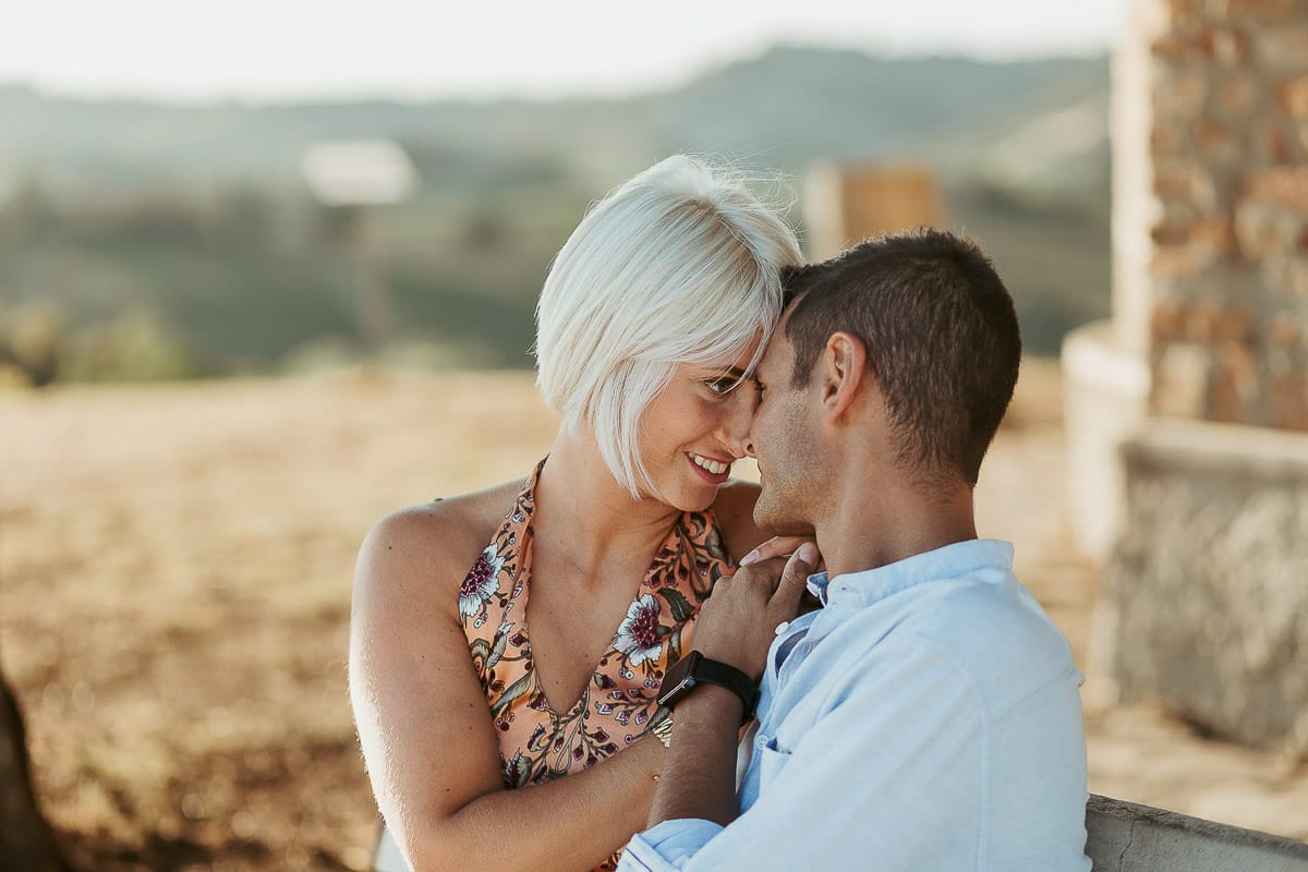 Prewedding da sogno a Nizza Monferrato intorno alla chiesa della Madonna della Neve. Matteo e Fiammetta seduti su di una panchina all'ombra di un grande albero. si guardano intensamente