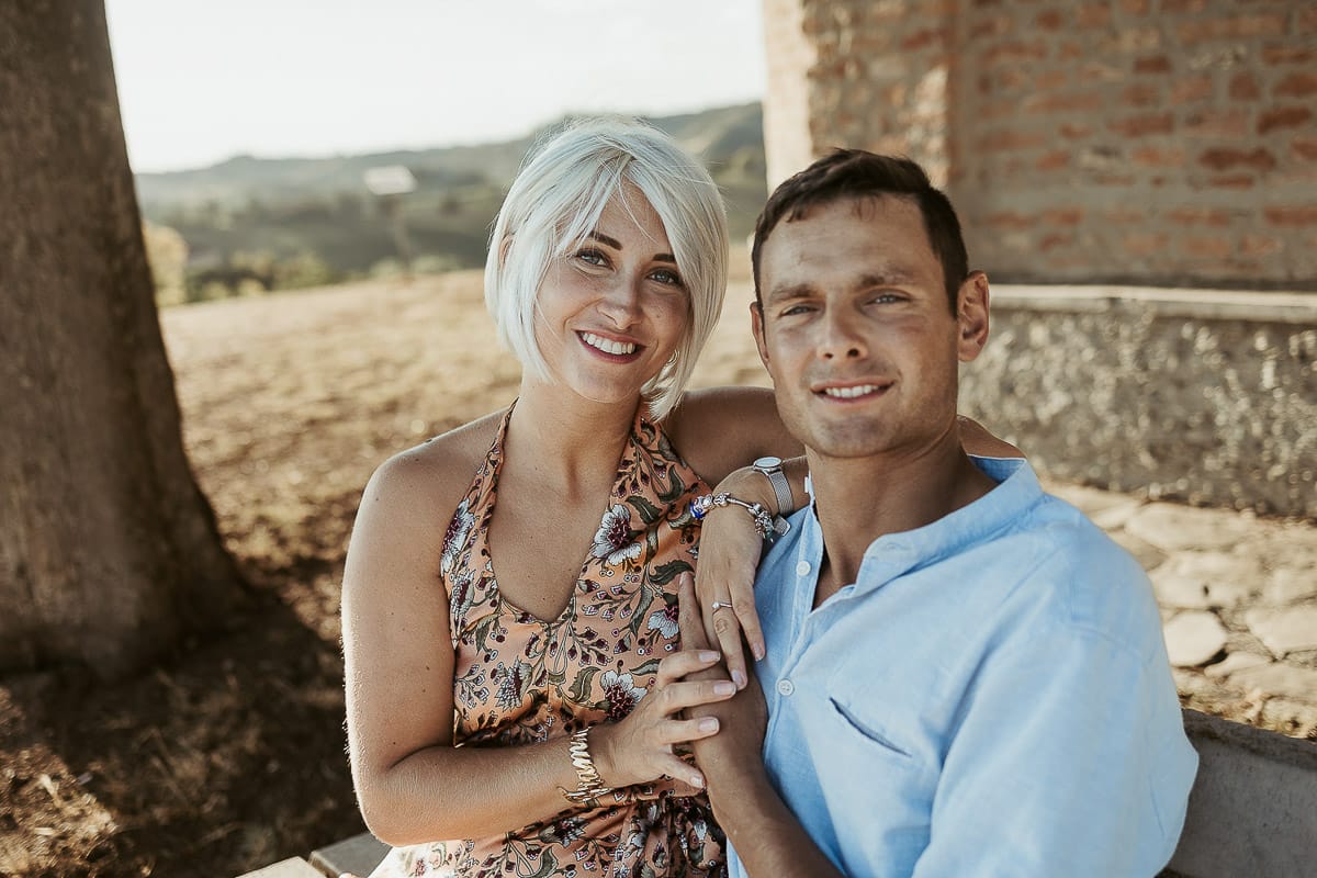 Prewedding da sogno a Nizza Monferrato intorno alla chiesa della Madonna della Neve. Matteo e Fiammetta seduti su di una panchina all'ombra di un grande albero.