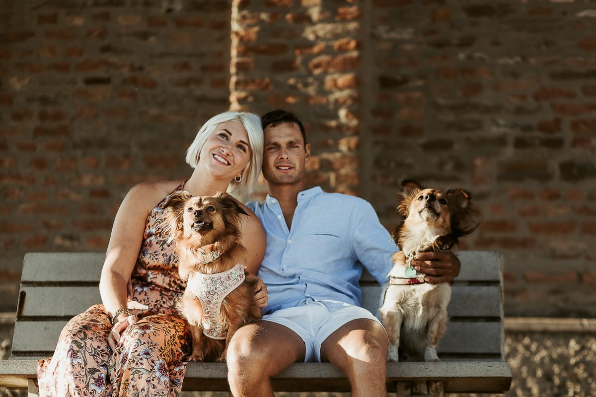 Prewedding da sogno a Nizza Monferrato intorno alla chiesa della Madonna della Neve. Matteo e Fiammetta seduti su di una panchina all'ombra di un grande albero con i volpini Megan e Harry.