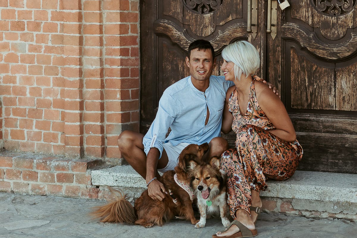 Prewedding da sogno a Nizza Monferrato intorno alla chiesa della Madonna della Neve. Fiammetta e Matteo seduti sul gradino del portone della chiesa con i loro volpini Megan e Harry
