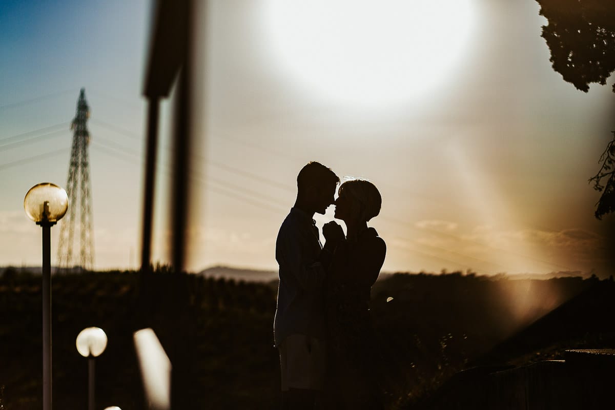 Prewedding da sogno a Nizza Monferrato intorno alla chiesa della Madonna della Neve. Matteo e Fiammetta camminano lungo il vialetto verso i vigneti. Ritratto in controluce, silhouette