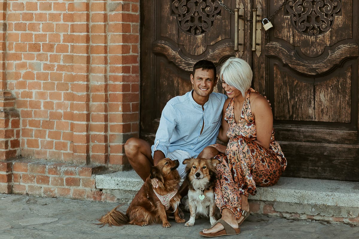 Prewedding da sogno a Nizza Monferrato intorno alla chiesa della Madonna della Neve. Fiammetta e Matteo seduti sul gradino del portone della chiesa con i loro volpini Megan e Harry