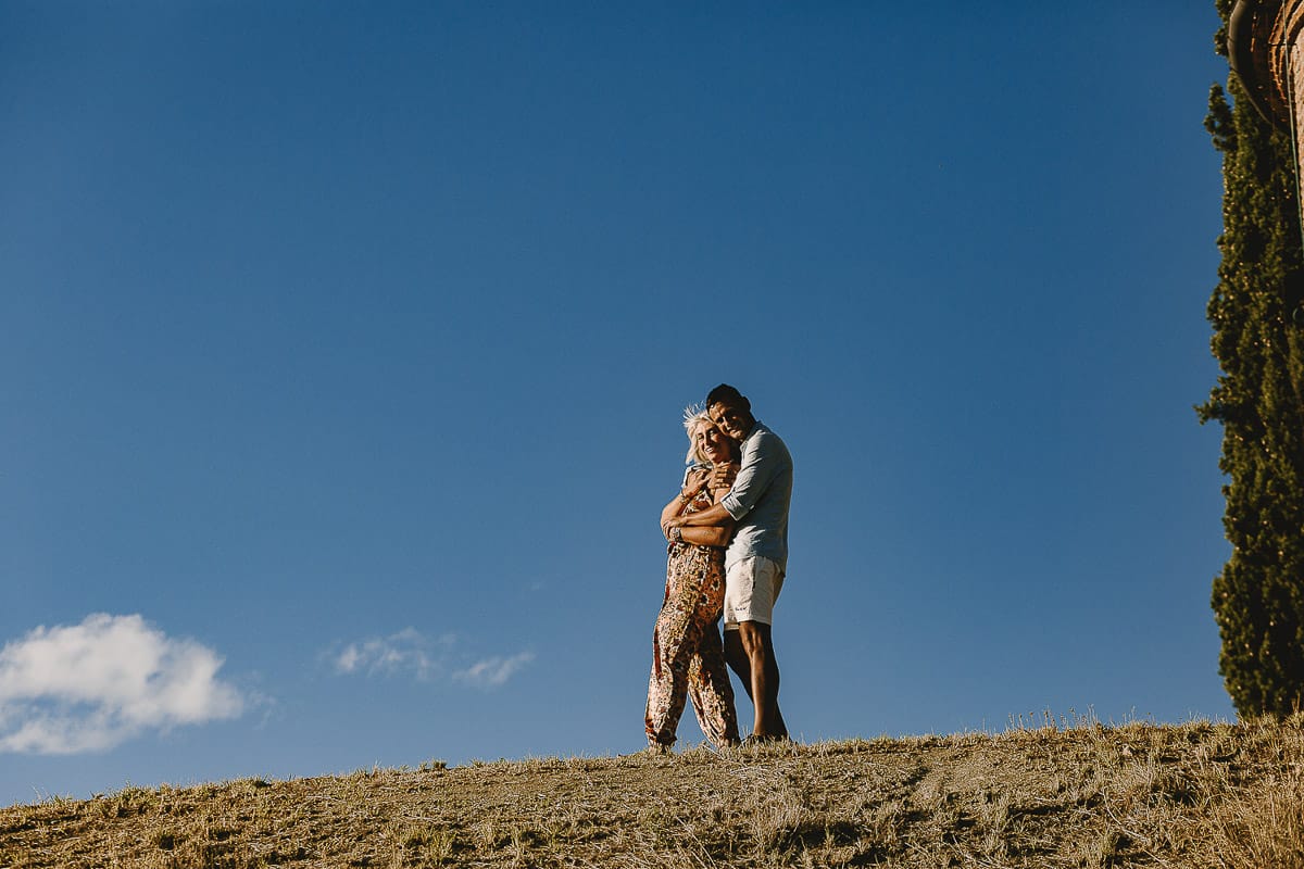 Prewedding da sogno a Nizza Monferrato intorno alla chiesa della Madonna della Neve. Matteo abbraccia Fiammetta. Foto ripresa dal basso. La coppia si staglia nell'azzurro del cielo estivo.