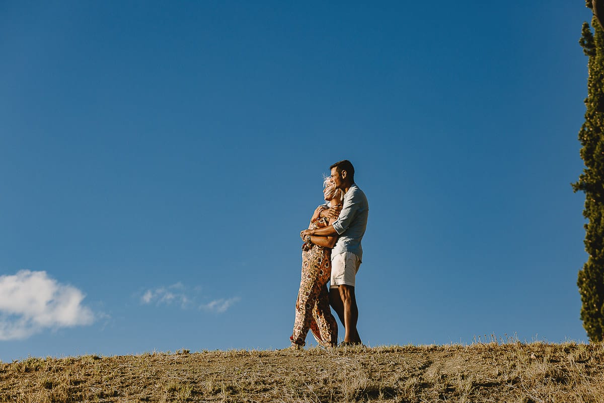 Prewedding da sogno a Nizza Monferrato intorno alla chiesa della Madonna della Neve. Matteo abbraccia Fiammetta. Foto ripresa dal basso. La coppia si staglia nell'azzurro del cielo estivo.