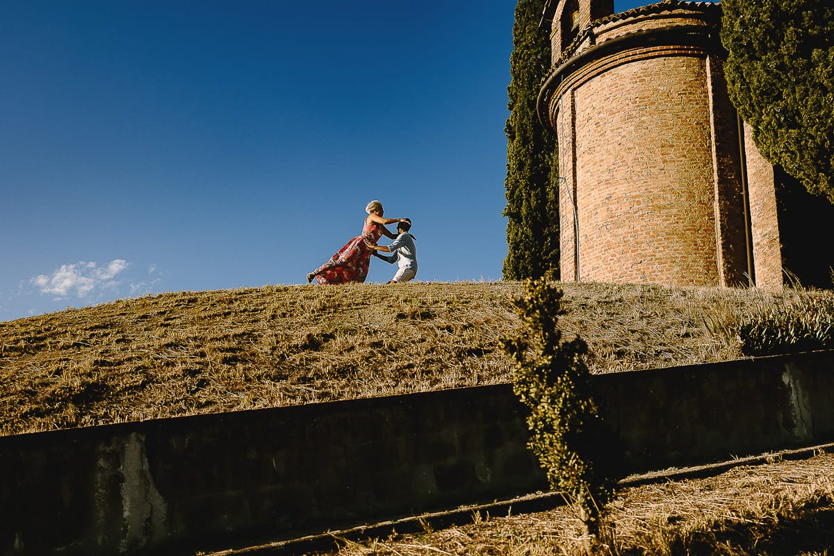 Prewedding da sogno a Nizza Monferrato intorno alla chiesa della Madonna della Neve. Matteo abbraccia Fiammetta. Foto ripresa dal basso. La coppia si staglia nell'azzurro del cielo estivo.