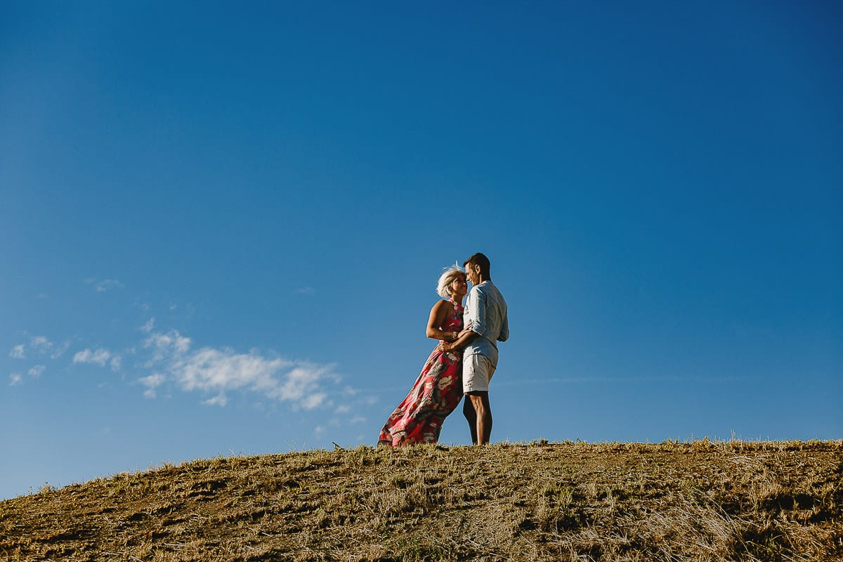 Prewedding da sogno a Nizza Monferrato intorno alla chiesa della Madonna della Neve. Matteo abbraccia Fiammetta. Foto ripresa dal basso. La coppia si staglia nell'azzurro del cielo estivo.