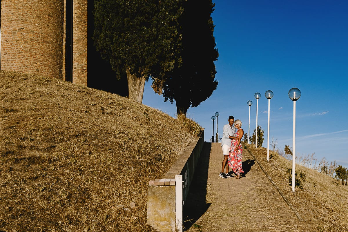 Prewedding da sogno a Nizza Monferrato intorno alla chiesa della Madonna della Neve. Fiammetta e matteo scendono dal vialetto verso il vigneto.