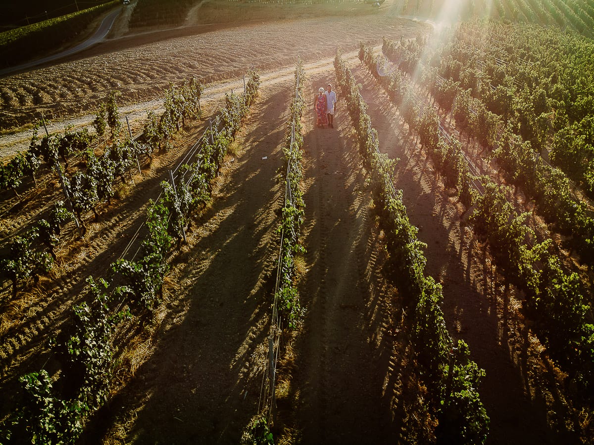 Prewedding da sogno a Nizza Monferrato intorno alla chiesa della Madonna della Neve. Fiammetta e Matteo nel vigneto. Foto aerea dal drone con il flare del sole che sta tramontando.