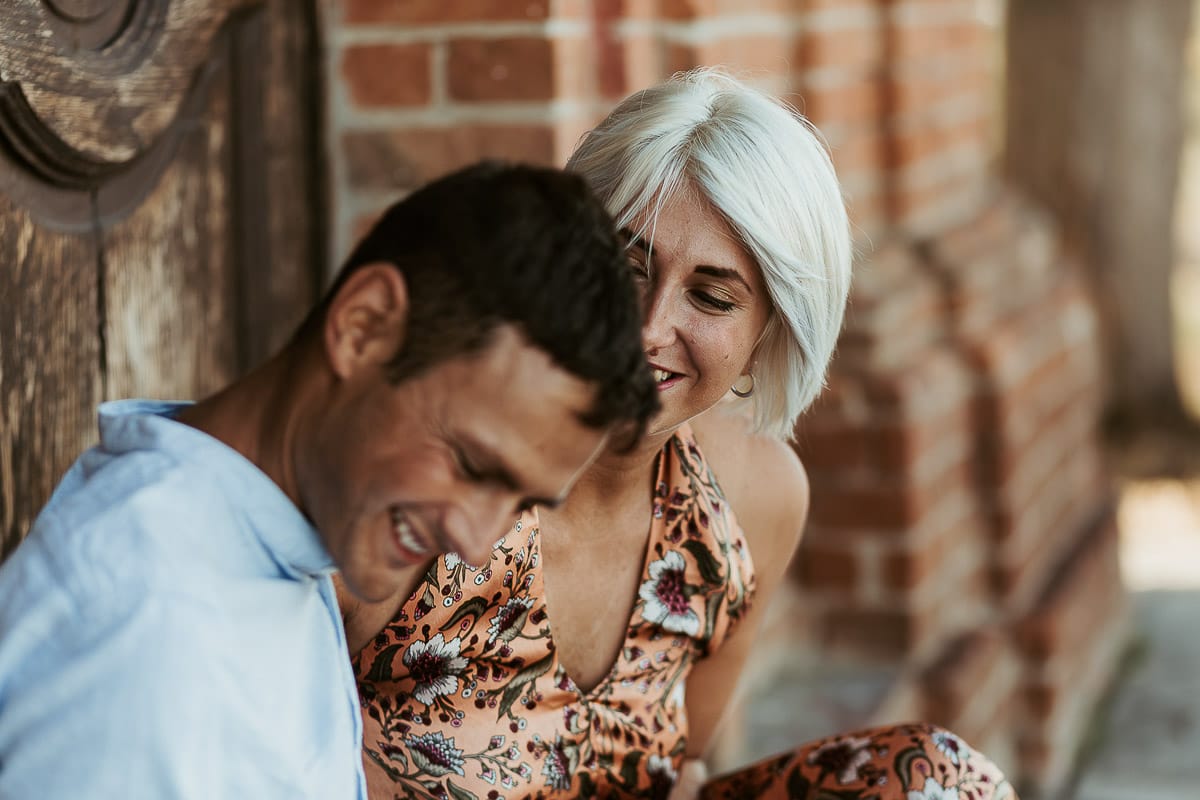Prewedding da sogno a Nizza Monferrato intorno alla chiesa della Madonna della Neve. Fiammetta e Matteo seduti sul gradino del portone della chiesa con i loro volpini Megan e Harry