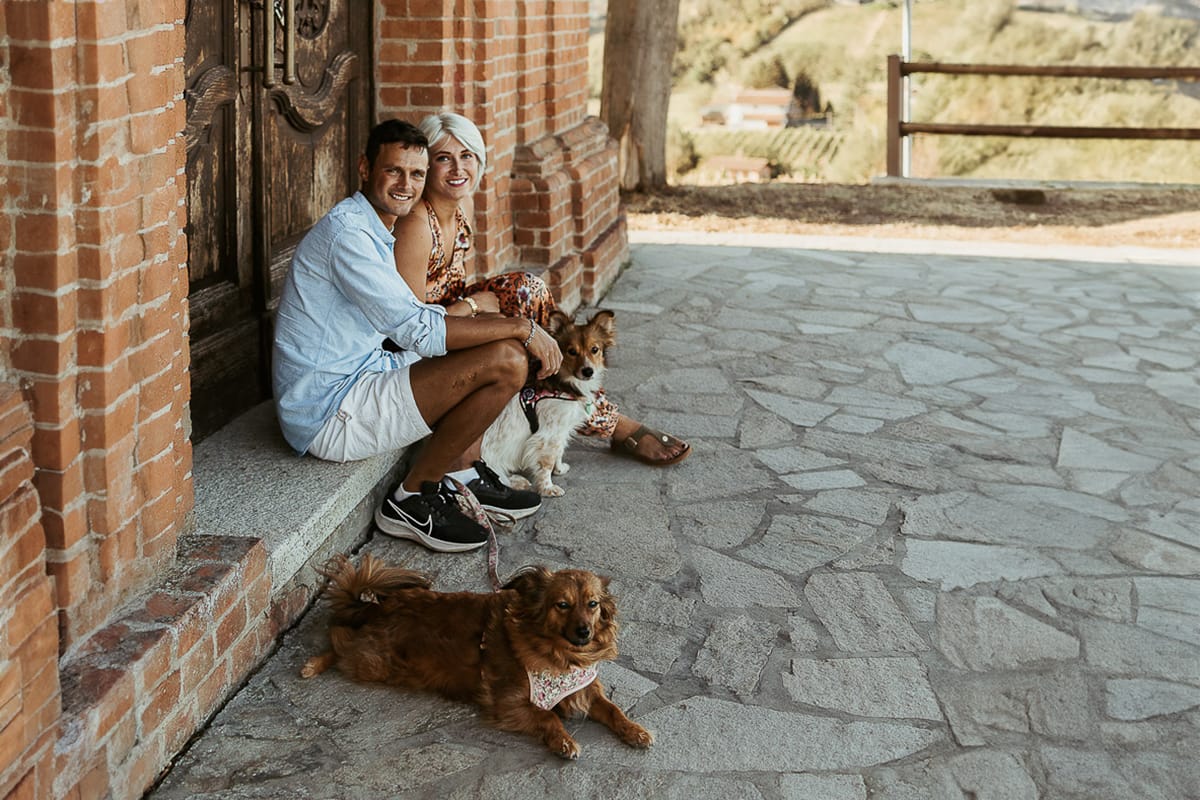 Prewedding da sogno a Nizza Monferrato intorno alla chiesa della Madonna della Neve. Fiammetta e Matteo seduti sul gradino del portone della chiesa con i loro volpini Megan e Harry
