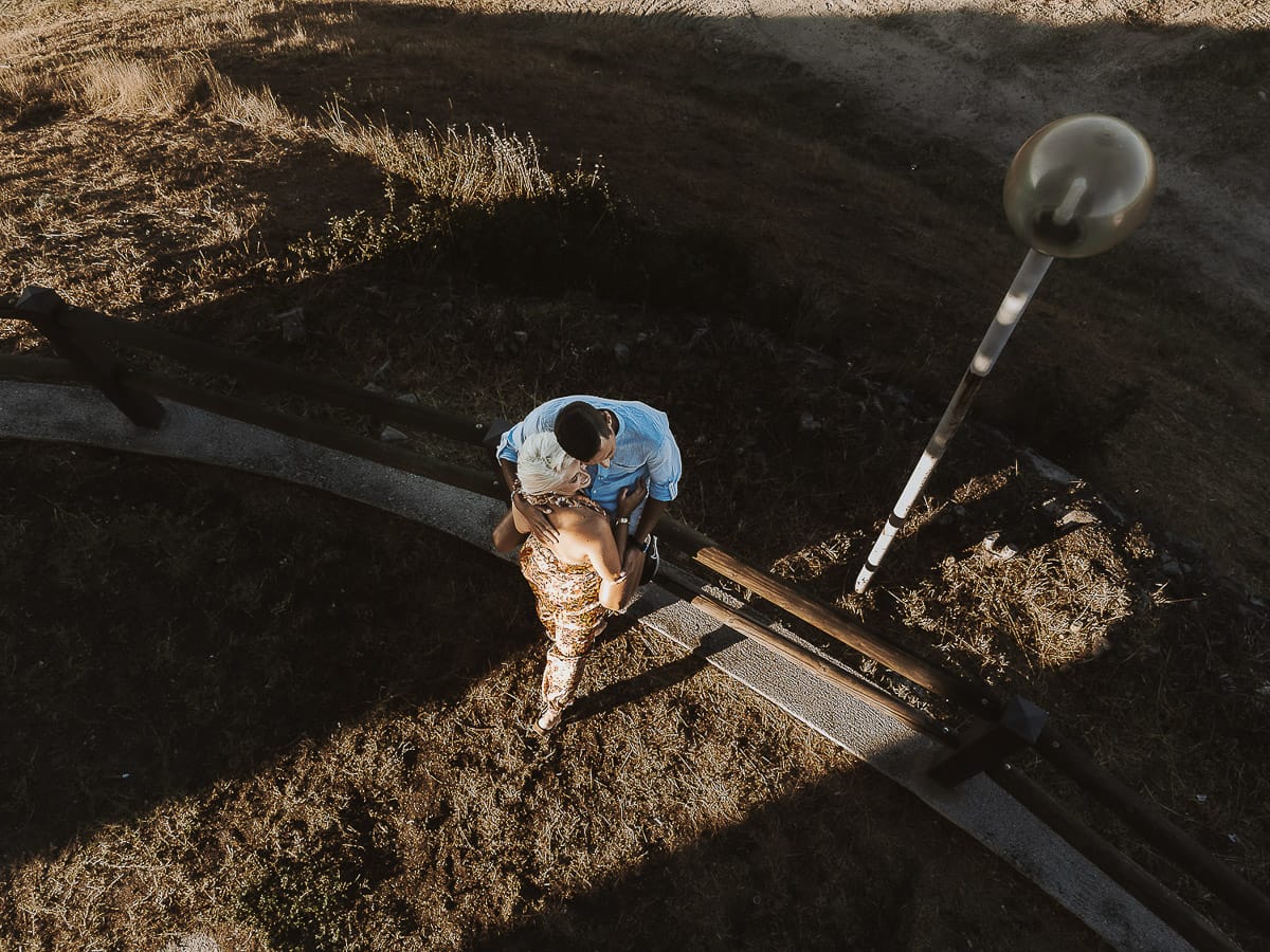 Prewedding da sogno a Nizza Monferrato intorno alla chiesa della Madonna della Neve. Matteo seduto su di una staccionata di legno abbraccia Fiammetta. Foto dal drone.