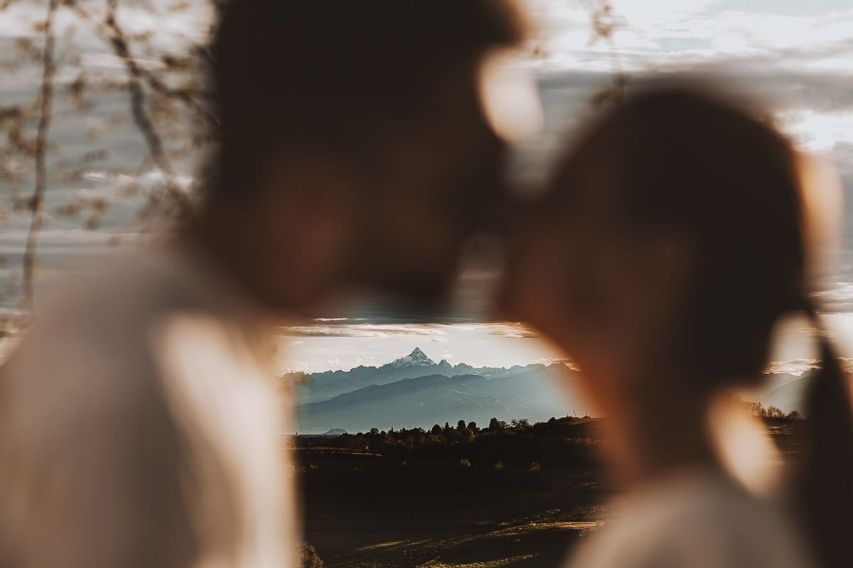 Prewedding spontaneo e poetico nel Monferrato a Mombello di Torino. Federica e Riccardo si baciano tra di loro in lontananza le Alpi, con la vetta del Monviso.