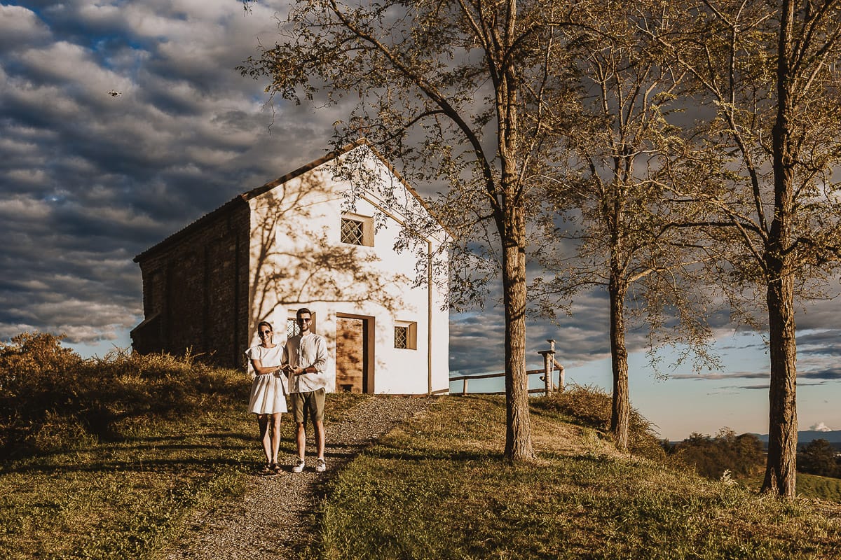 Prewedding spontaneo e poetico nel Monferrato a Mombello di Torino. Federica e Riccardo camminano tenendosi per mano davanti alla chiesa di san Lorenzo
