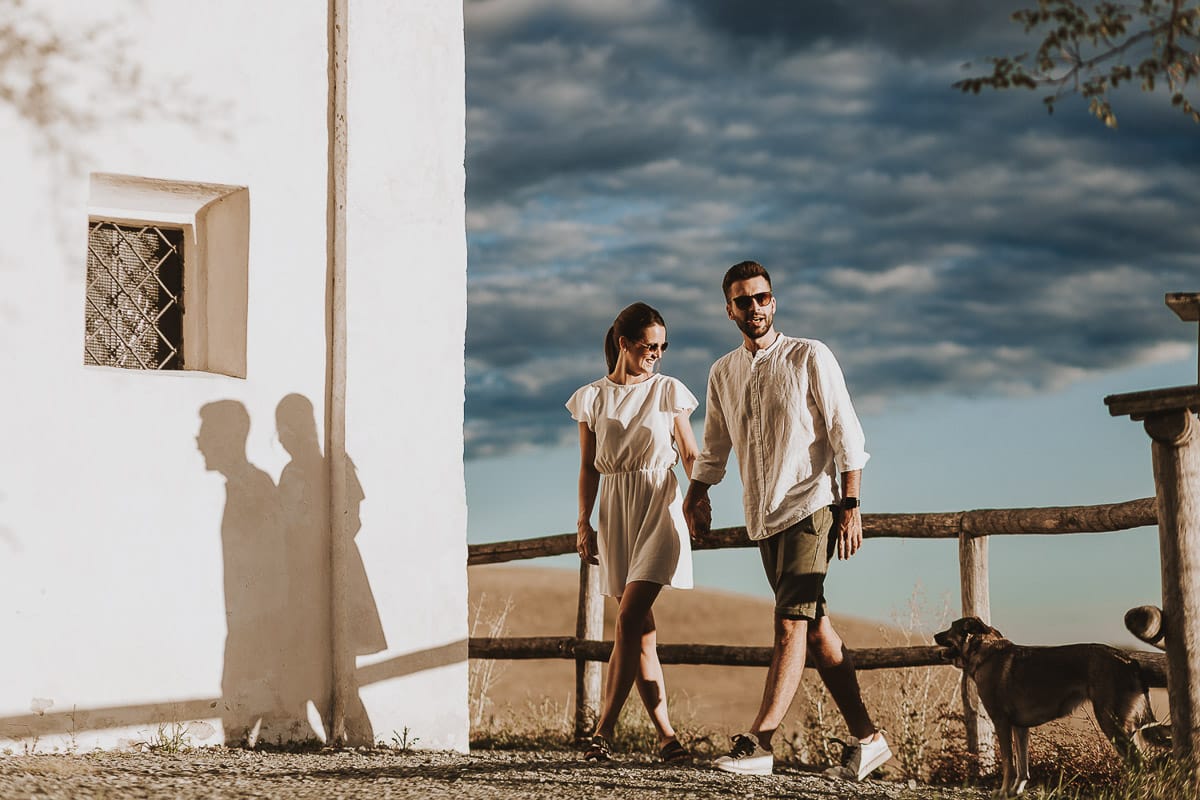 Prewedding spontaneo e poetico nel Monferrato a Mombello di Torino. Federica e Riccardo camminano tenendosi per mano. La cagnolina Macarena li guarda.