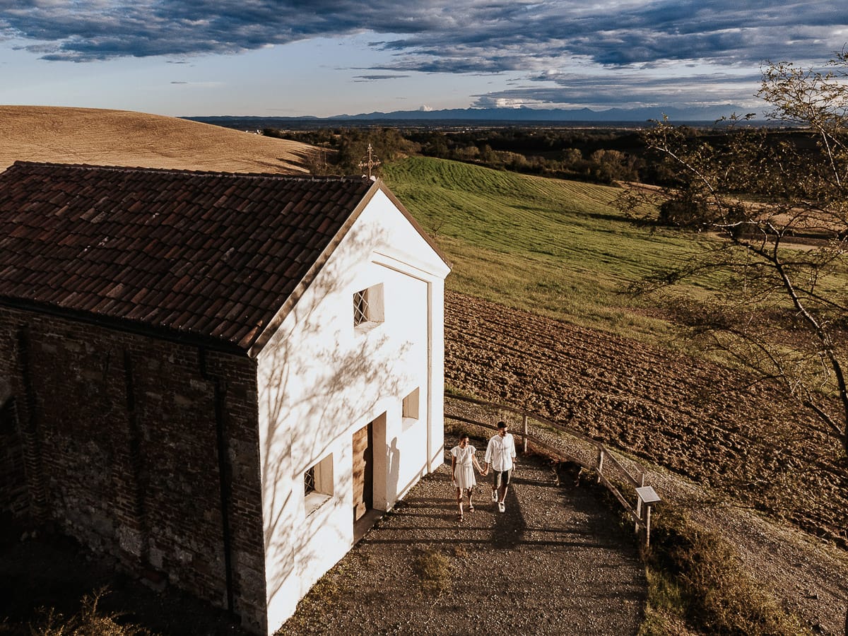 Prewedding spontaneo e poetico nel Monferrato a Mombello di Torino. Federica e Riccardo camminano tenendosi per mano. Foto panoramica dal drone