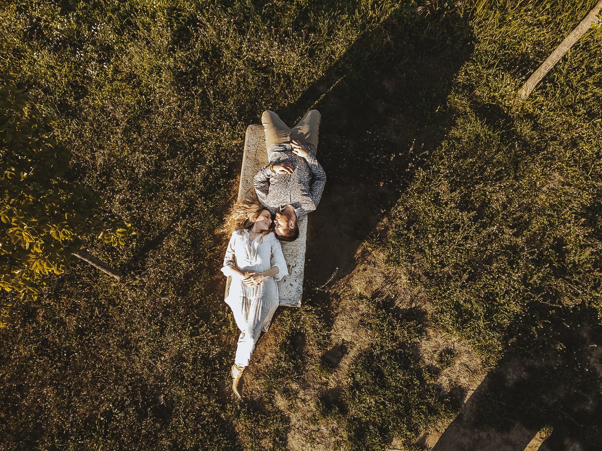 Un romantico ritratto di Anita e Davide, in procinto di convolare a nozze, in una splendida giornata primaverile. La coppia si trova di fronte a una chiesetta romanica a Mombello di Torino, nel cuore del Monferrato. La coppia è sdraiata su di una panchina. Foto ripresa dal drone.