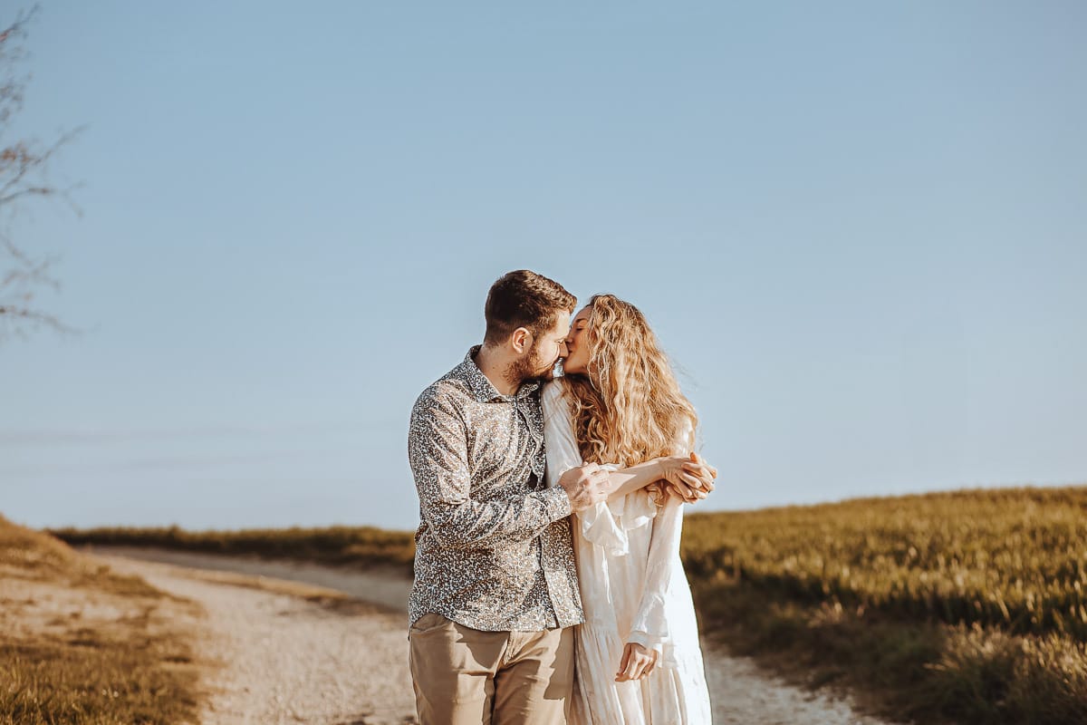 Mombello di Torino, Monferrato: Anita e Davide, raggianti di felicità, si scambiano un bacio davanti a una chiesetta romanica in un pittoresco pomeriggio primaverile. La foto cattura l'amore e l'emozione che precedono il loro matrimonio.