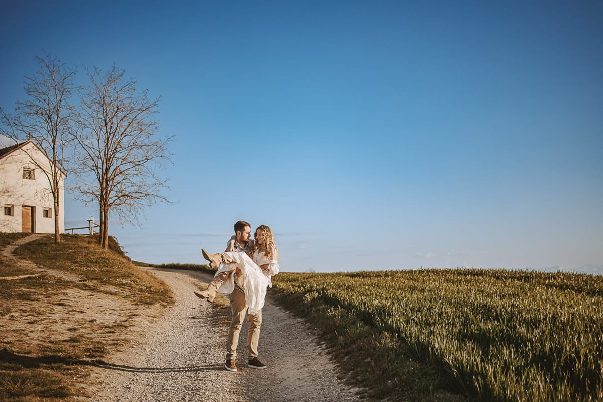 Un romantico ritratto di Anita e Davide, futuri sposi, in una soleggiata giornata di inizio primavera. La coppia passeggia davanti alla chiesetta romanica di San Lorenzo a Mombello di Torino, godendo della bellezza del panorama del Monferrato. Davide prende in braccio Anita