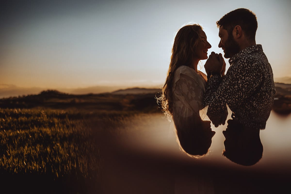 Mombello di Torino, Monferrato: Anita e Davide, futuri sposi, si scambiano un bacio davanti alla chiesetta di San Lorenzo. La foto in controluce crea un'atmosfera magica e romantica, simbolo del loro amore e della loro promessa di vita insieme.