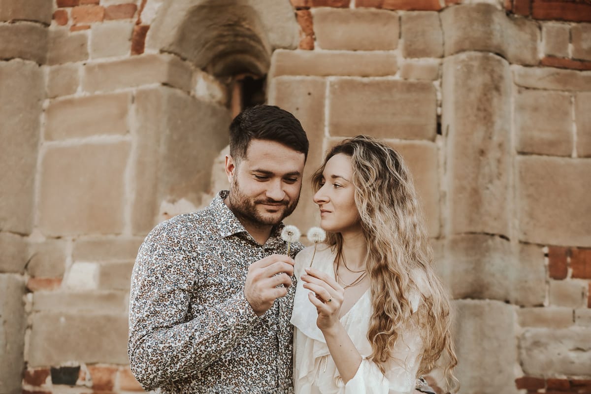 Un ritratto romantico di Anita e Davide, futuri sposi, in una soleggiata giornata primaverile. La coppia si trova di fronte a una chiesetta romanica a Mombello di Torino, nel cuore del Monferrato la coppia soffia un soffione