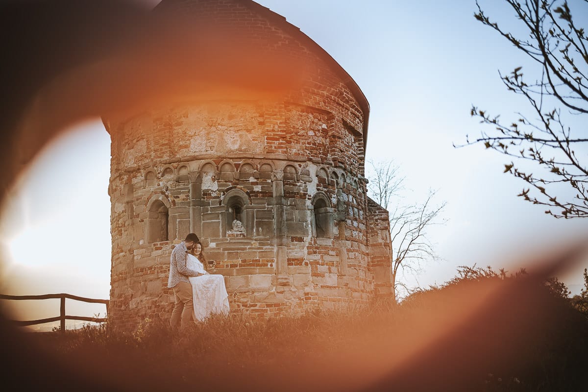 Un ritratto romantico di Anita e Davide, futuri sposi, in una soleggiata giornata primaverile. La coppia si trova di fronte a una chiesetta romanica a Mombello di Torino, nel cuore del Monferrato