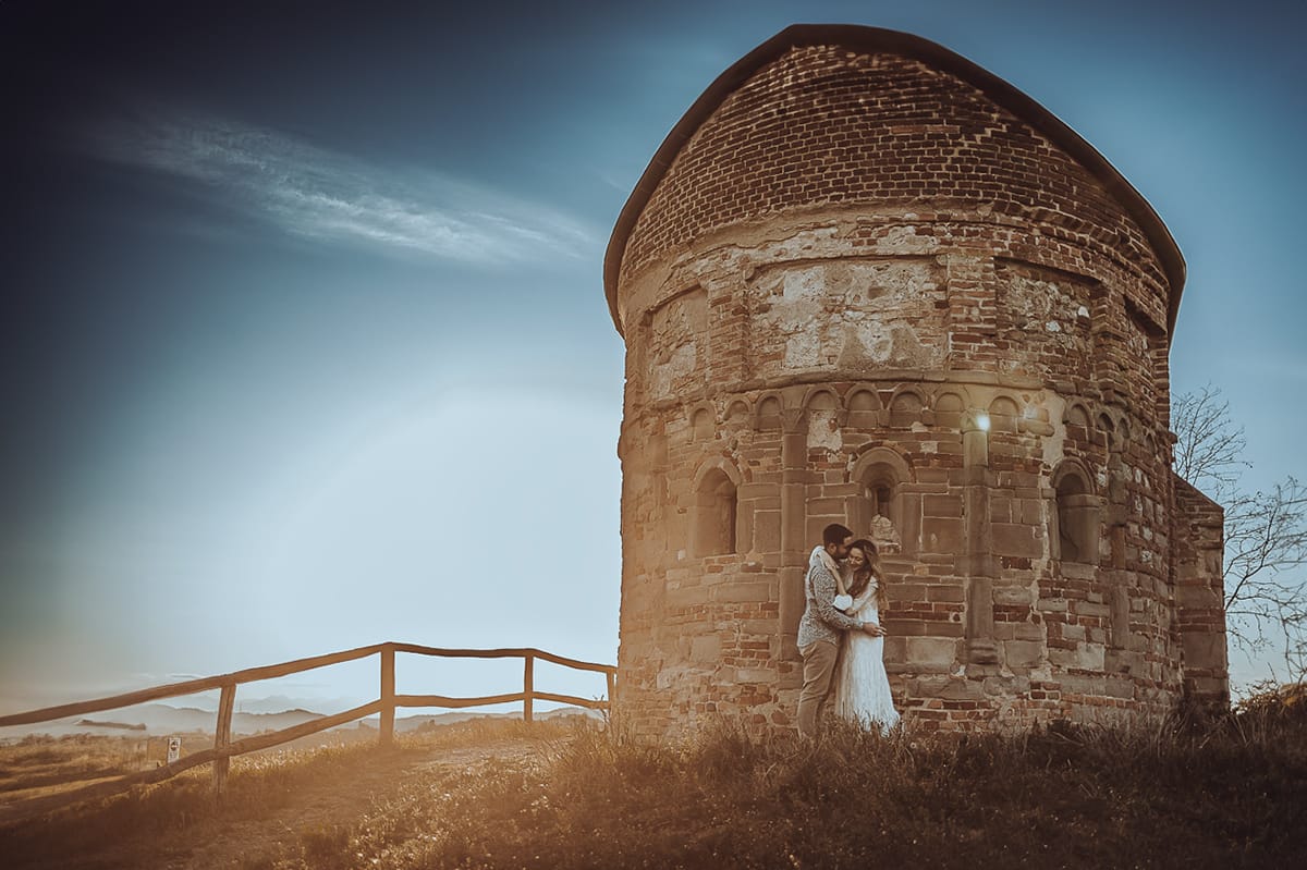 Un ritratto romantico di Anita e Davide, futuri sposi, in una soleggiata giornata primaverile. La coppia si trova di fronte a una chiesetta romanica a Mombello di Torino, nel cuore del Monferrato